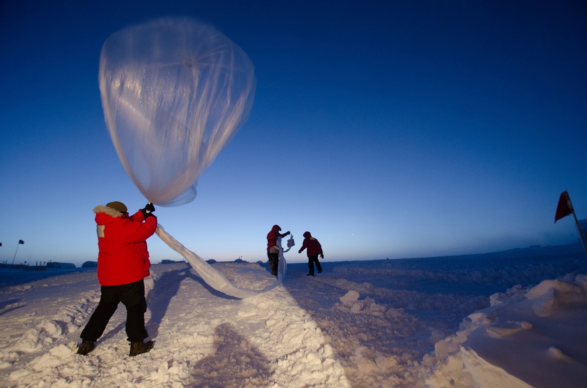 A man releasing a large silver balloon.