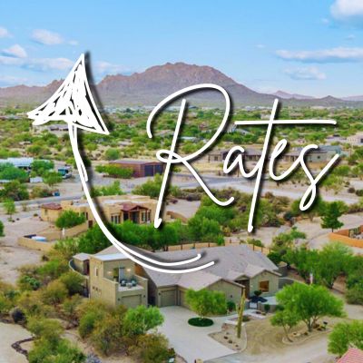 An aerial view of a neighborhood with mountains in the background. The word 'Rates' appears with an upward-pointing arrow.