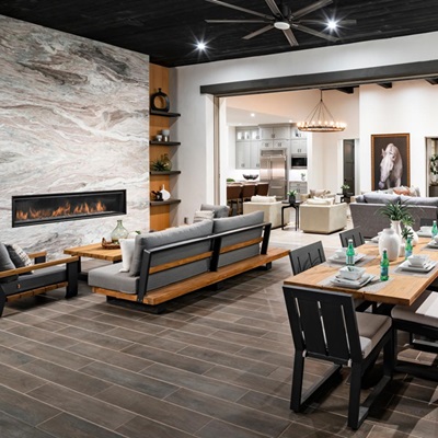 Elegant open-concept living room with a modern fireplace, comfortable seating, and wood accents, seamlessly flowing into a stylish kitchen area.