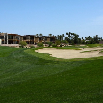 Luxury homes under construction next to a golf course with green grass and sand bunkers.