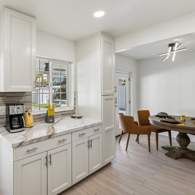 Kitchen with white cabinets, marble counters, and dining area.