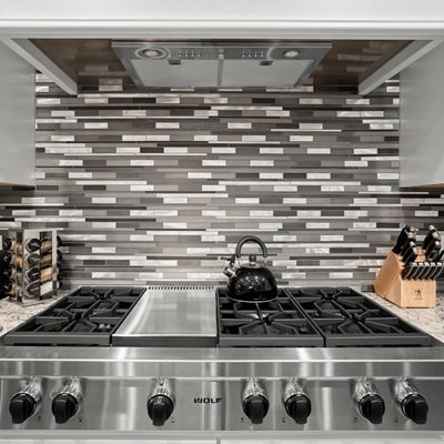 Modern stainless steel stove with sleek tile backsplash.