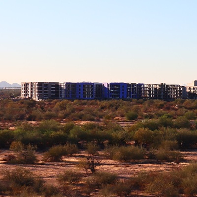 Portico Luxury Condos under construction, surrounded by desert landscape and mountain views.