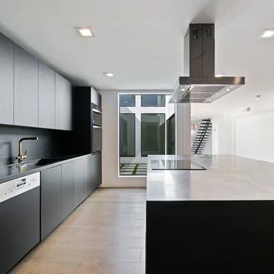 Sleek black kitchen with integrated appliances and large island.
