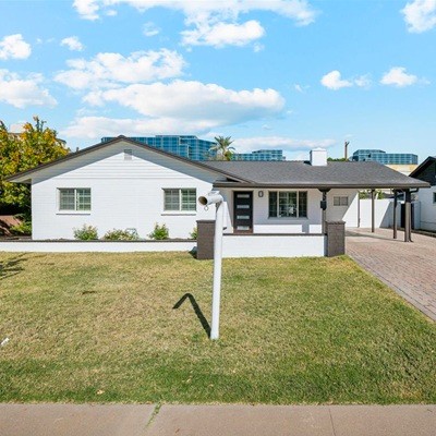 A single story home seen from the front as a blue sky with patchy clouds fill the sky.