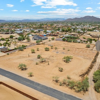 Blue skies with patchy clouds and a parcel of land seen from a drone.