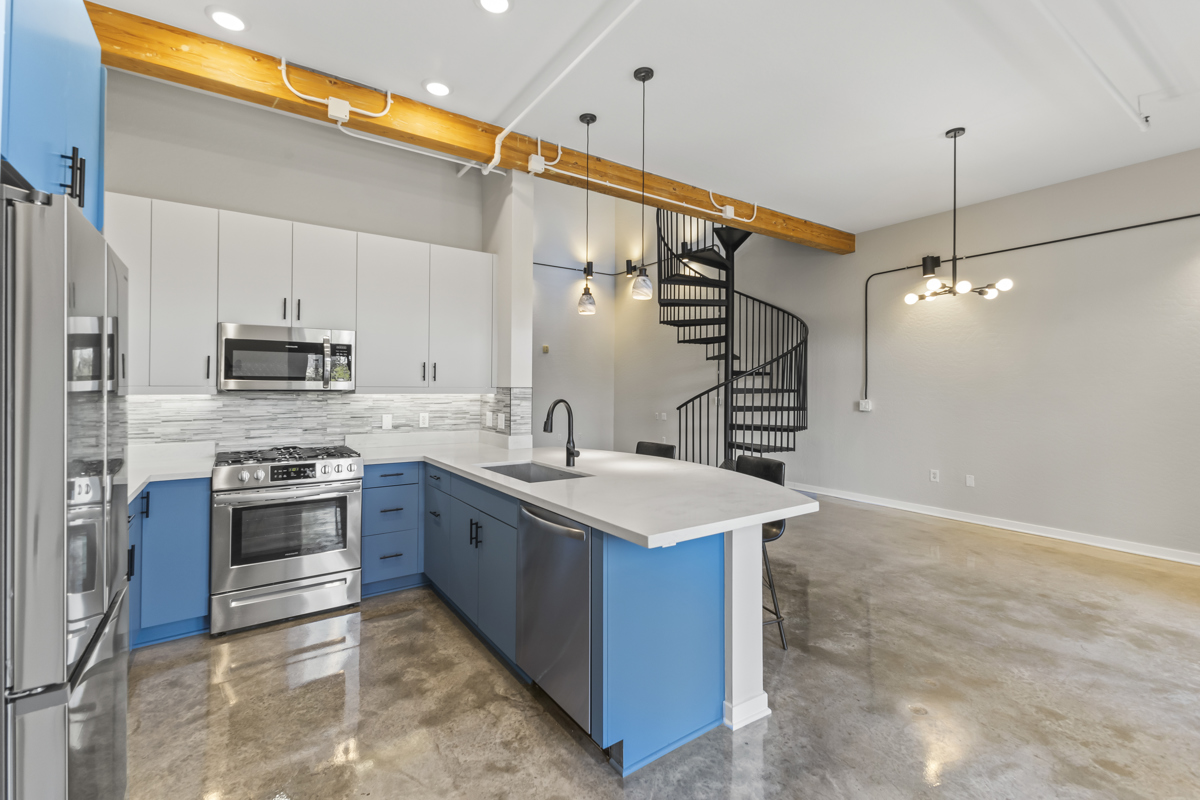 Modern kitchen with blue cabinets, stainless steel appliances.