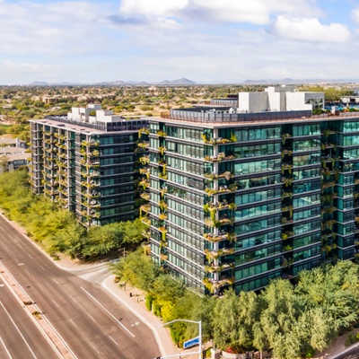 Modern mid-rise buildings with glass facades in Scottsdale, featuring green landscaping and clear views of surrounding suburban areas.