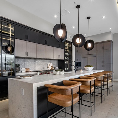 Modern kitchen with sleek black and wood cabinetry, a large marble island, and stylish pendant lighting.