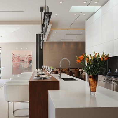 Modern kitchen with white countertops, bar stools, and decor.