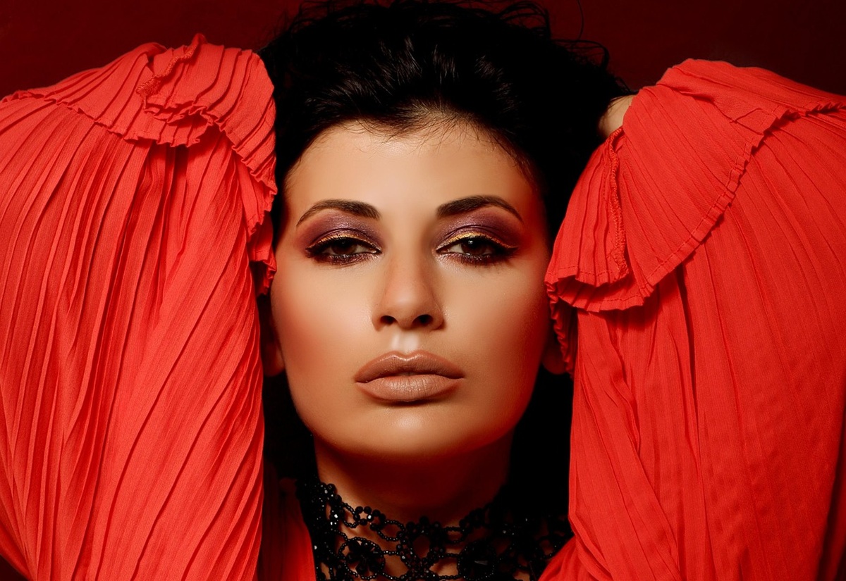 A dark-haired fashion model wearing red and looking into the camera.