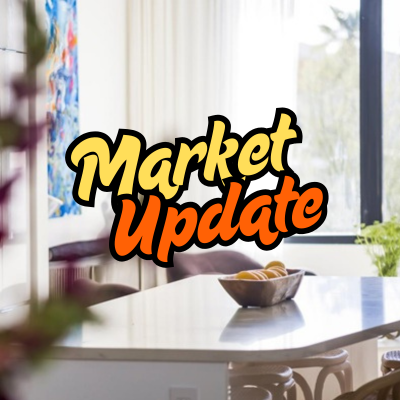 The words 'market update' written over a photo of an open kitchen with marble island, colorful art, and natural light.