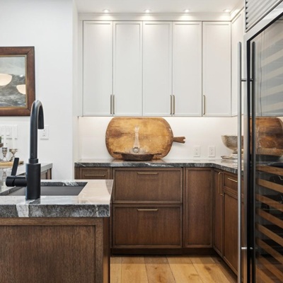 Modern kitchen with wood cabinets, marble countertops, and black faucet.