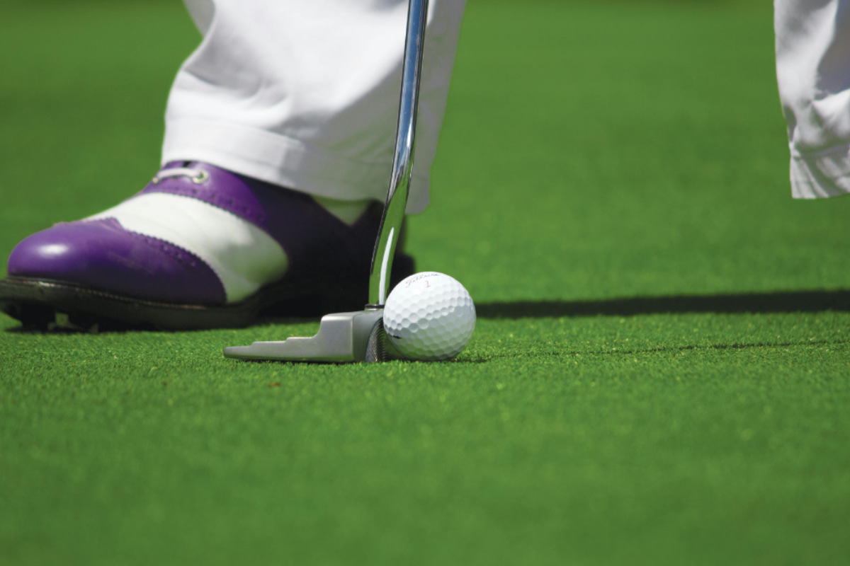 Man lining up club with golf ball on golf course