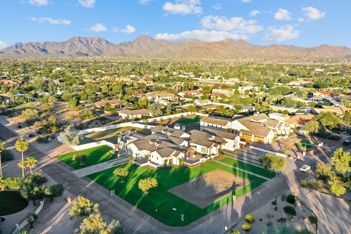 Large white Scottsdale home with gray roof and patio, backed by mountains.