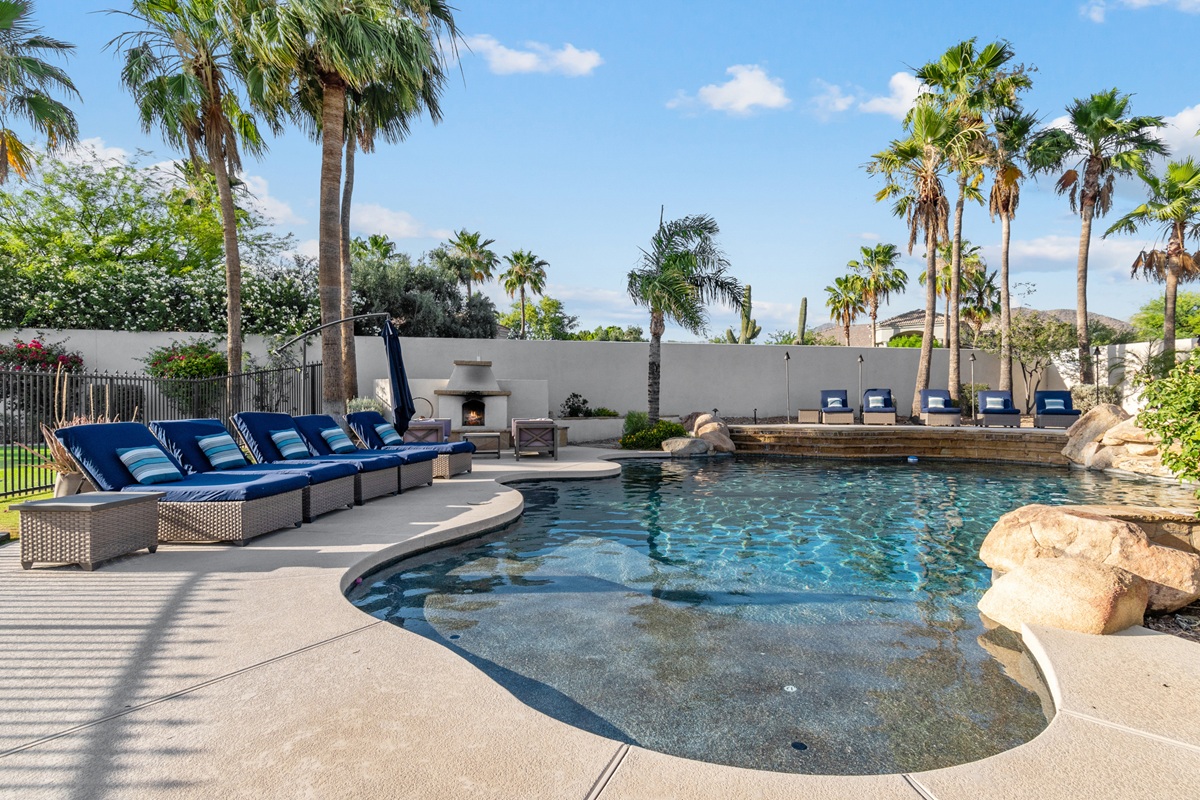 Pool and loungers in bacvkyard of a luxury home.