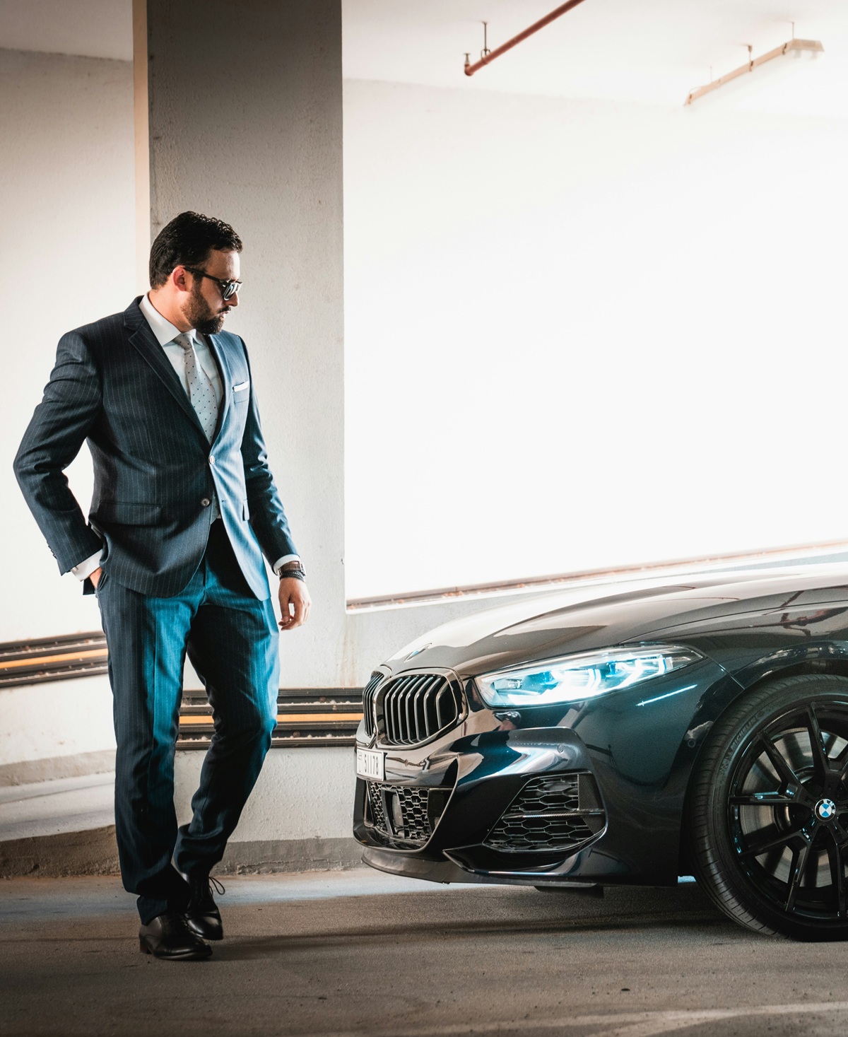 A wealthy man walking up to a sports car.