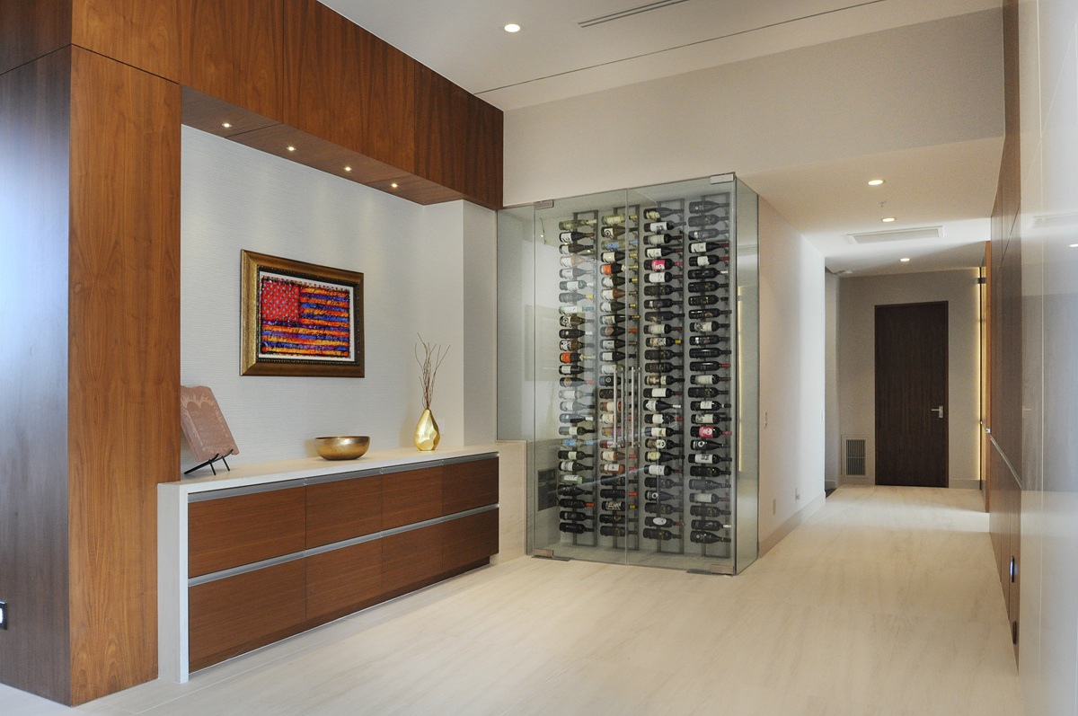 Modern hallway with glass wine cellar and art display.