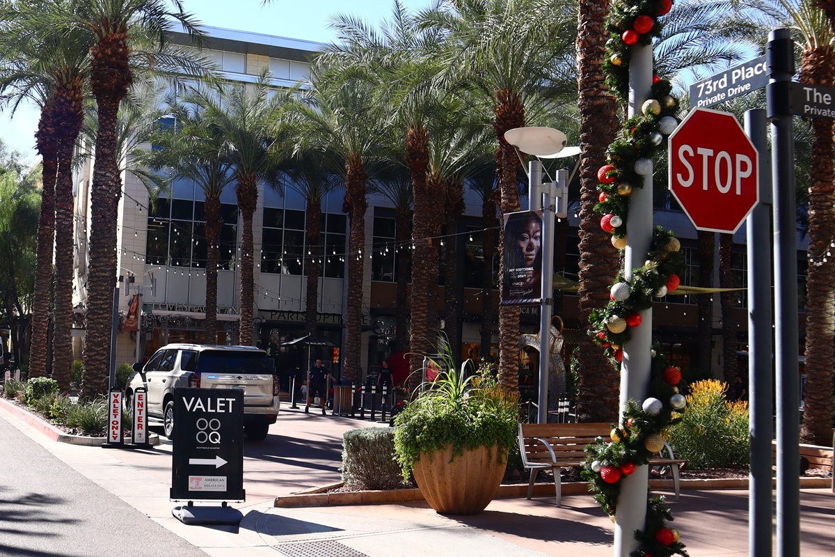 Valet area surrounded by palm trees and holiday decorations at Scottsdale Quarter, with a stop sign and a street sign for 73rd Place in view.