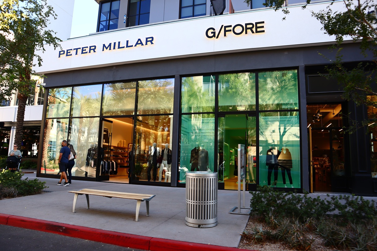 Storefronts of Peter Millar and G/Fore at Scottsdale Quarter, with mannequins in the window and a bench and trash can on the sidewalk