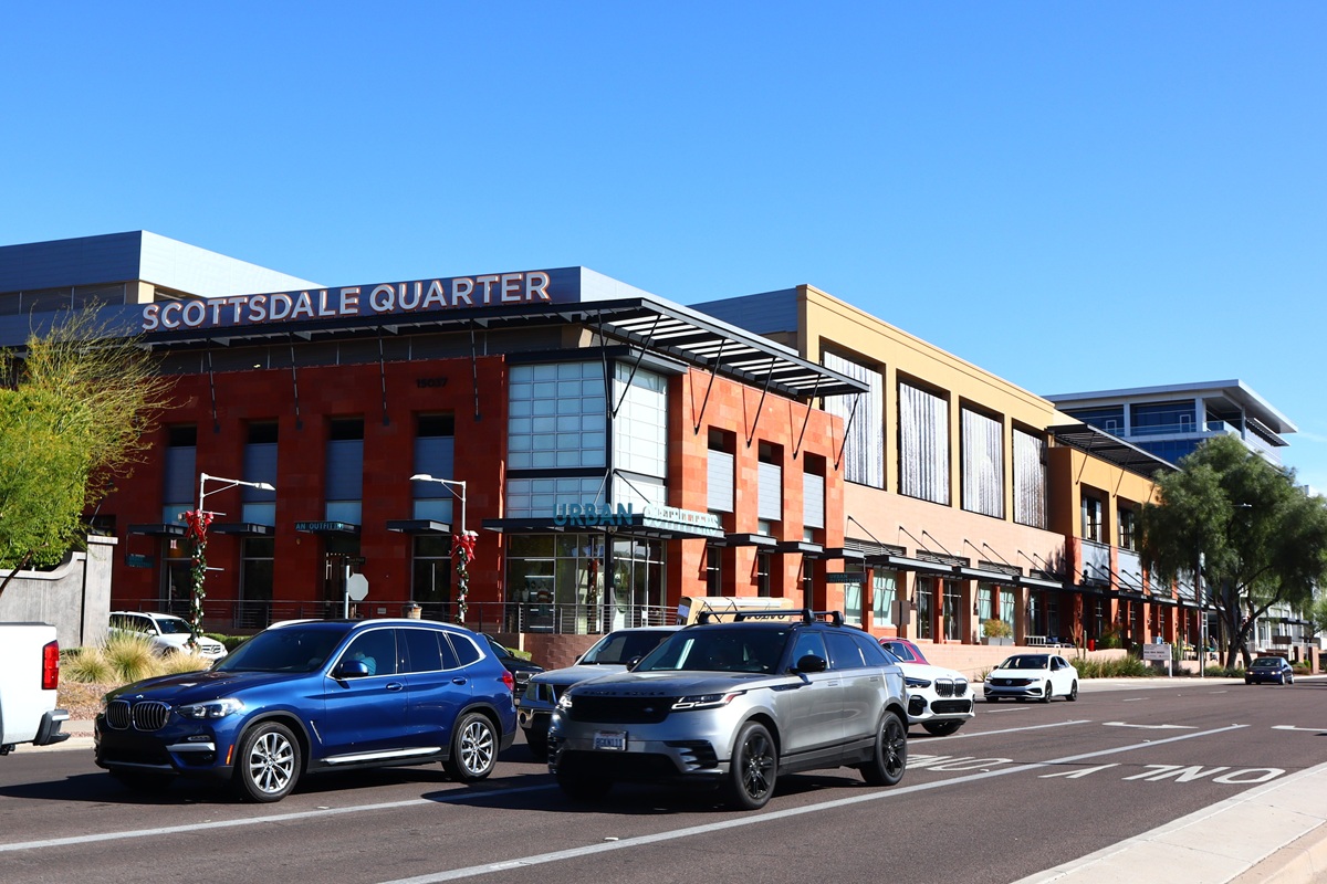 Exterior view of the Scottsdale Quarter shopping center with cars on the street and the Scottsdale Quarter sign atop the building.